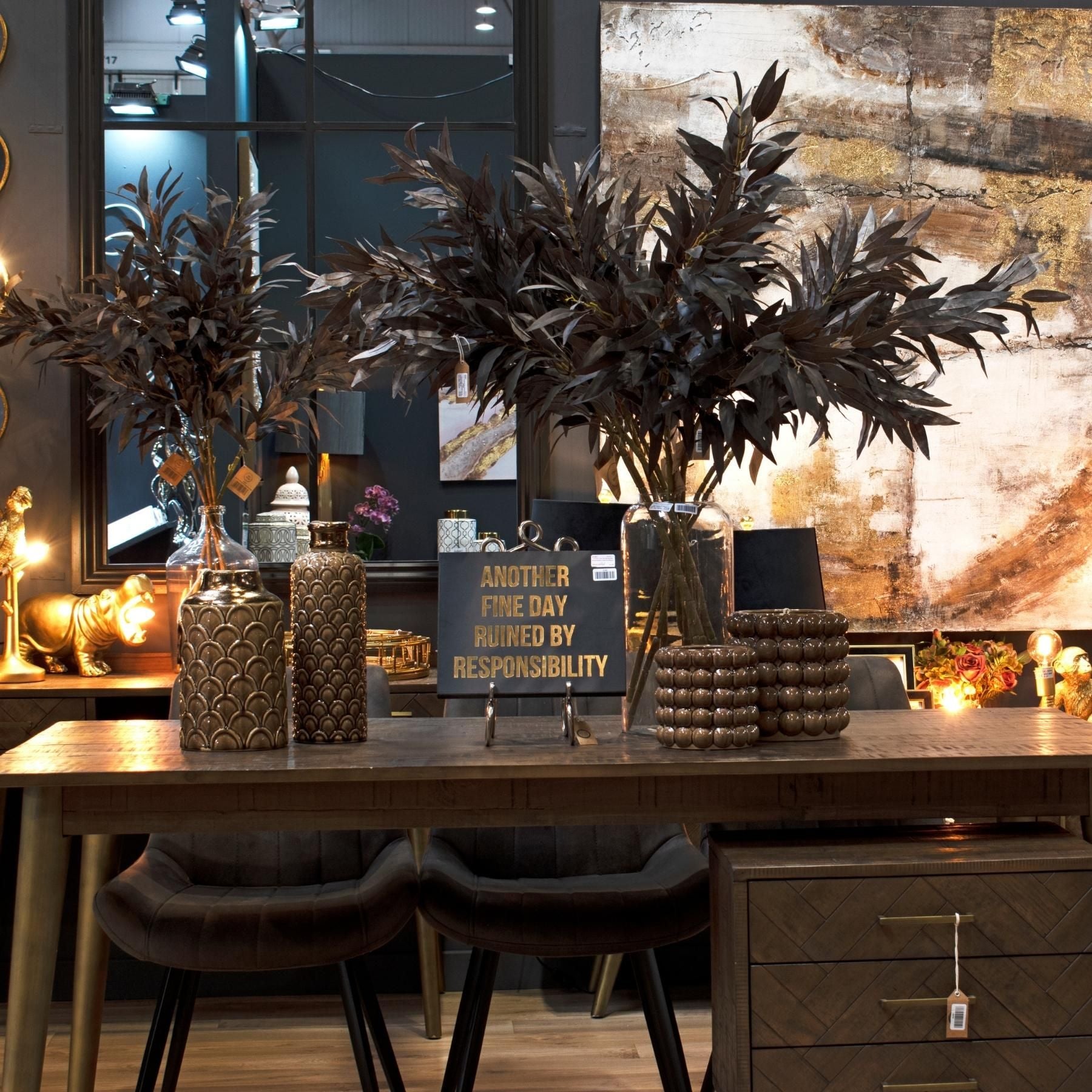 Decorative setup with potted plants, vases, and a motivational sign on a wooden table.