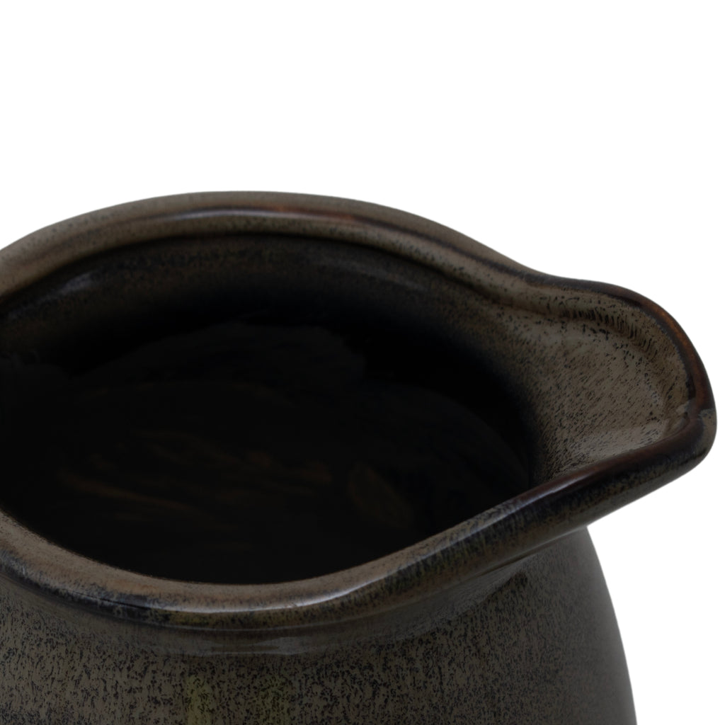 Close-up of a dark ceramic pot with a handle on a white background