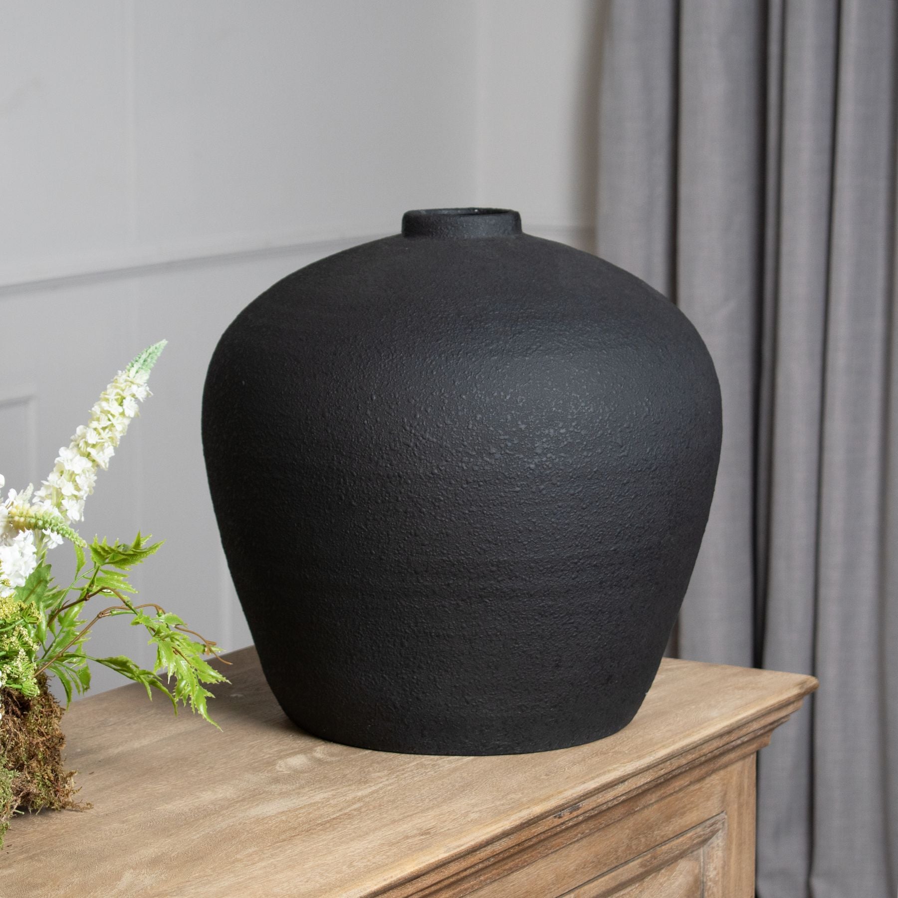 Black vase on a wooden surface with a neutral background