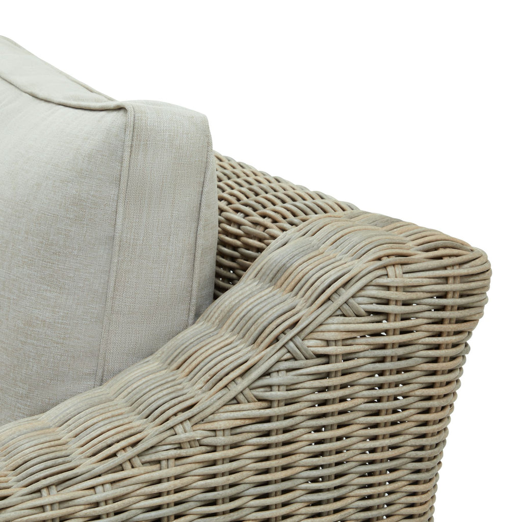 Close-up of a wicker chair with a beige cushion on a white background