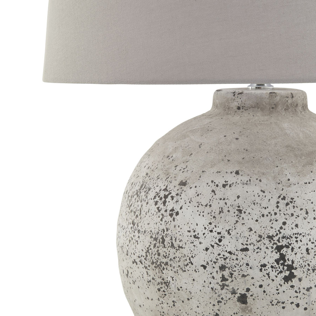 Table lamp with textured gray base and white shade on a white background