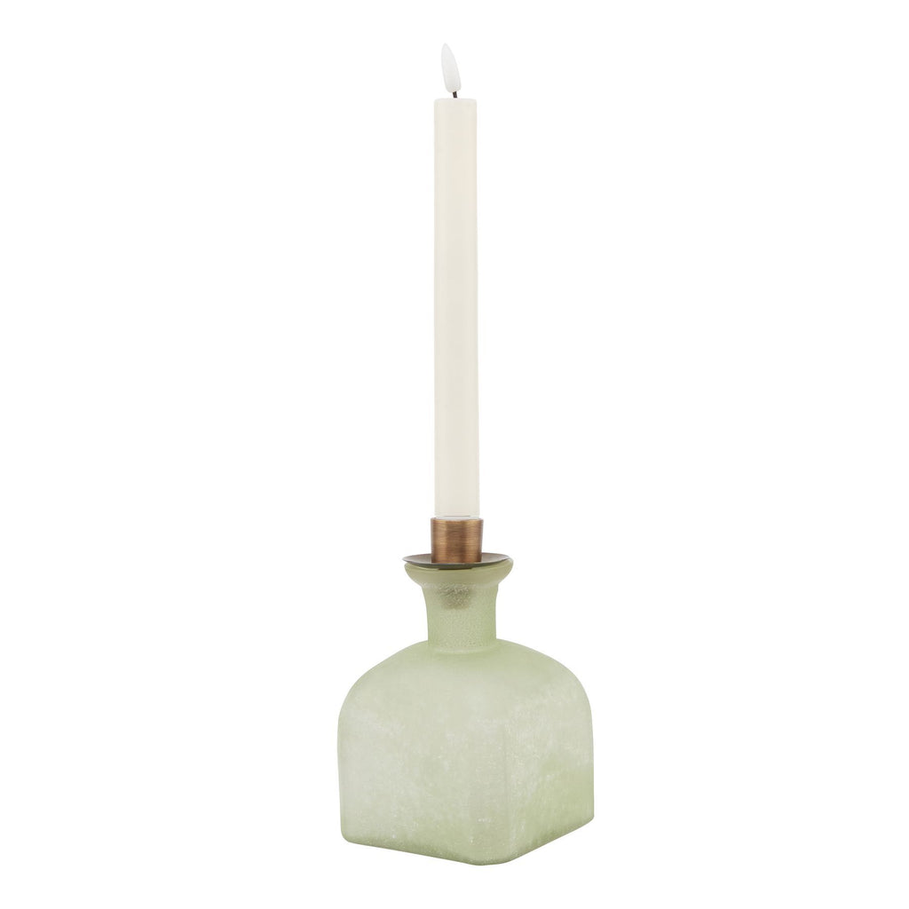 Green candle holder with a white candle on a white background