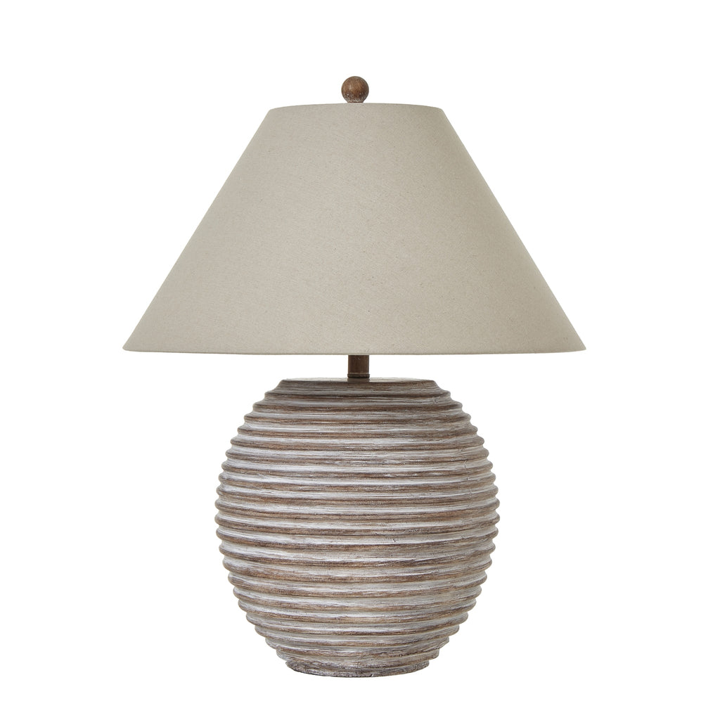 Table lamp with ribbed ceramic base and beige shade on a white background