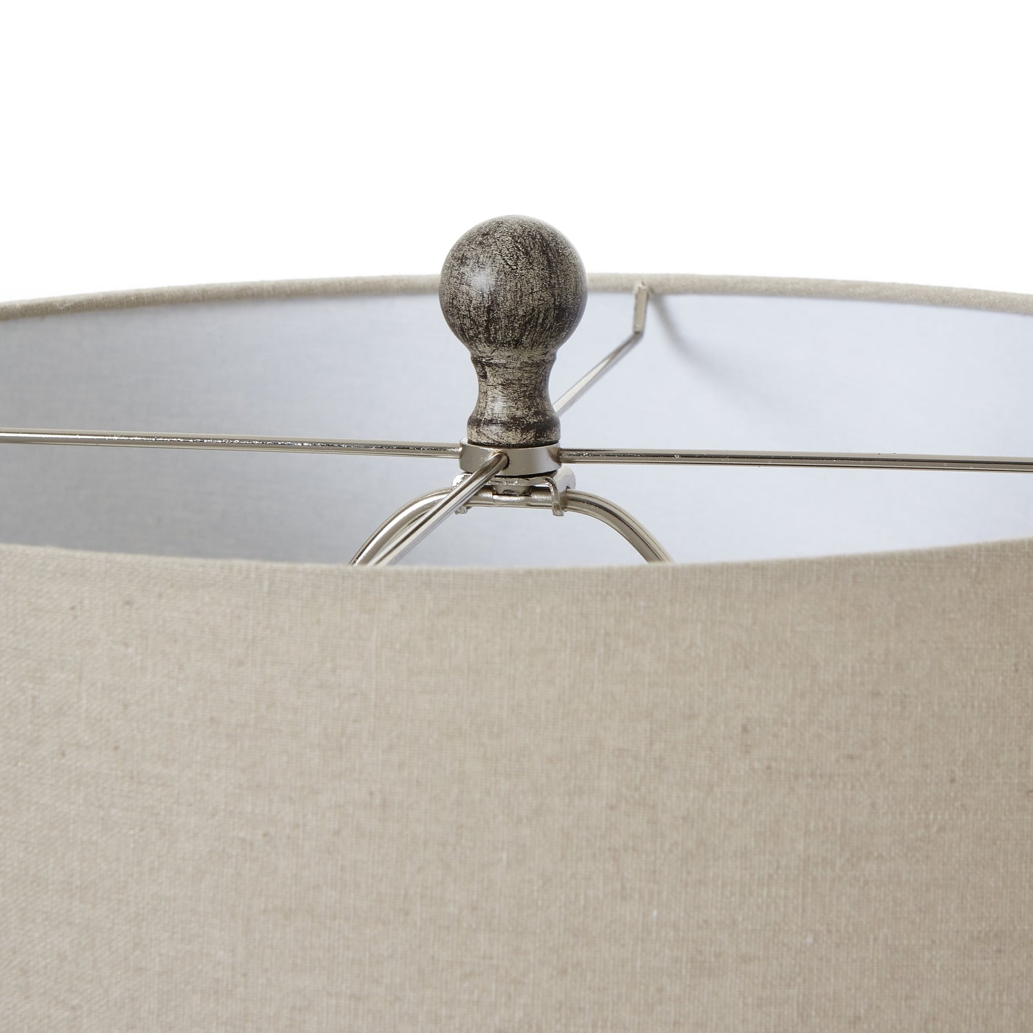 Close-up of a lamp with a beige shade and metallic base on a white background