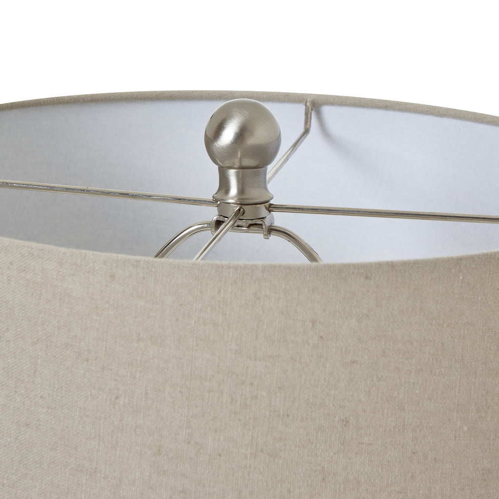 Close-up of a lamp with a beige fabric shade and metallic base.