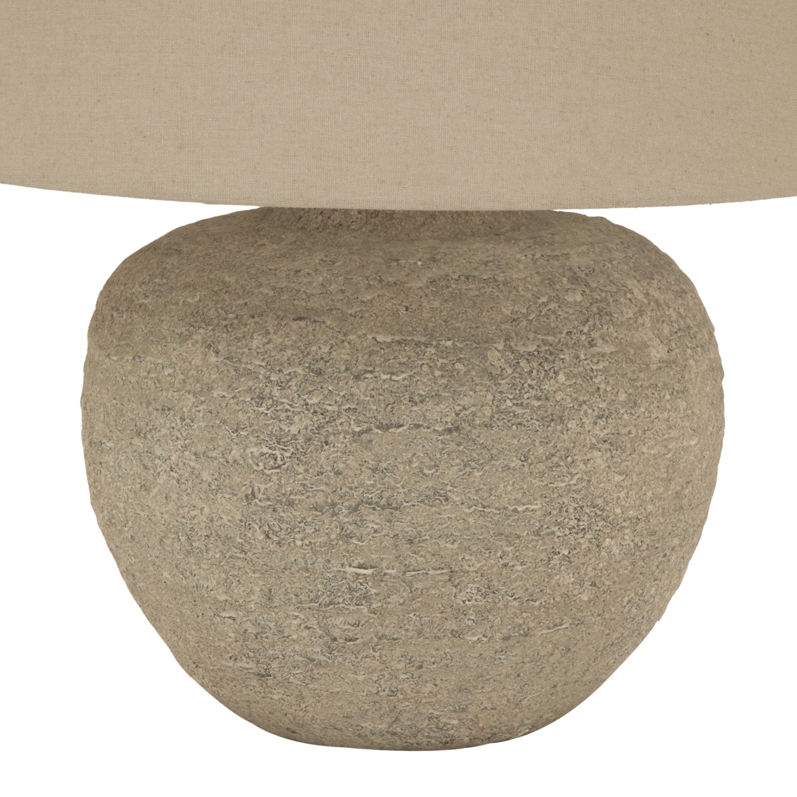 Close-up of a textured stone-like base with a beige lampshade above.