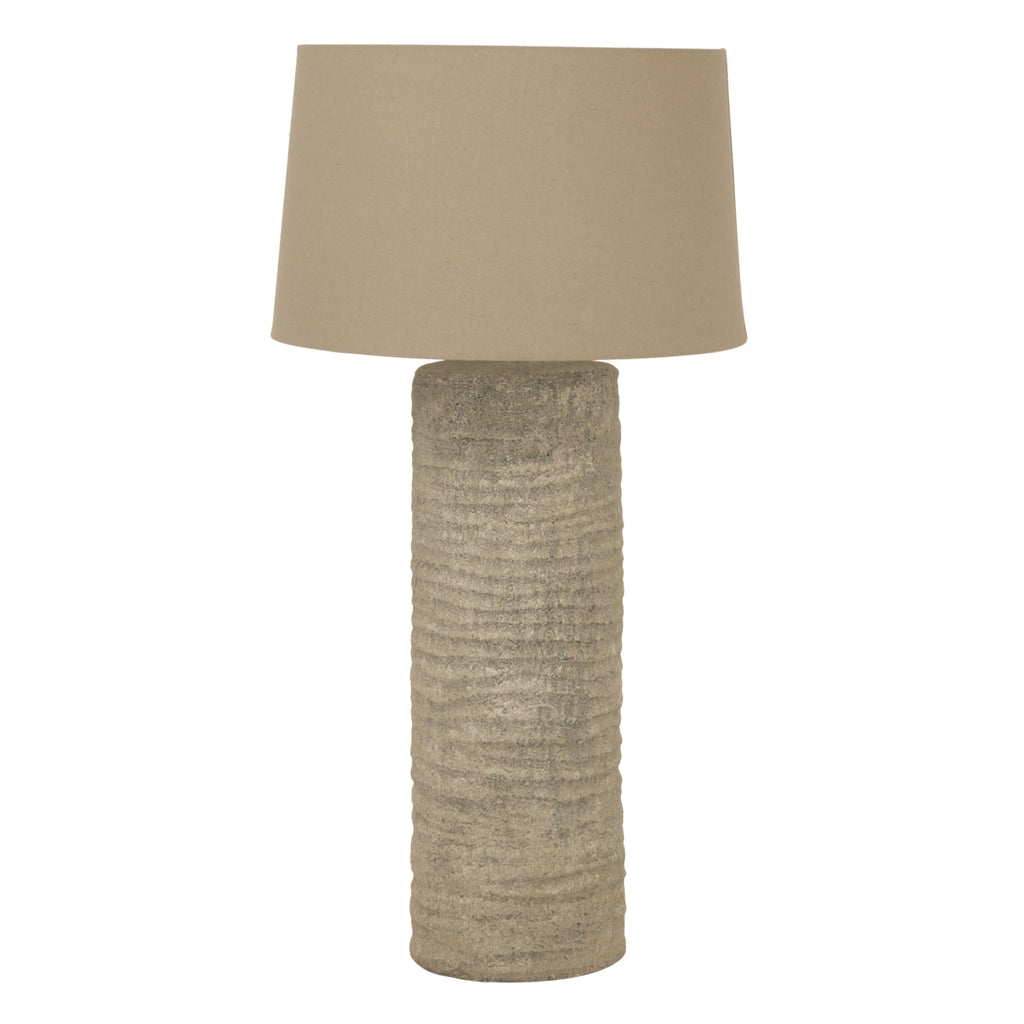 Table lamp with textured base and beige lampshade on a white background