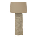 Table lamp with textured base and beige lampshade on a white background