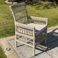 Wicker chair with a cushion on a patio area with grass in the background