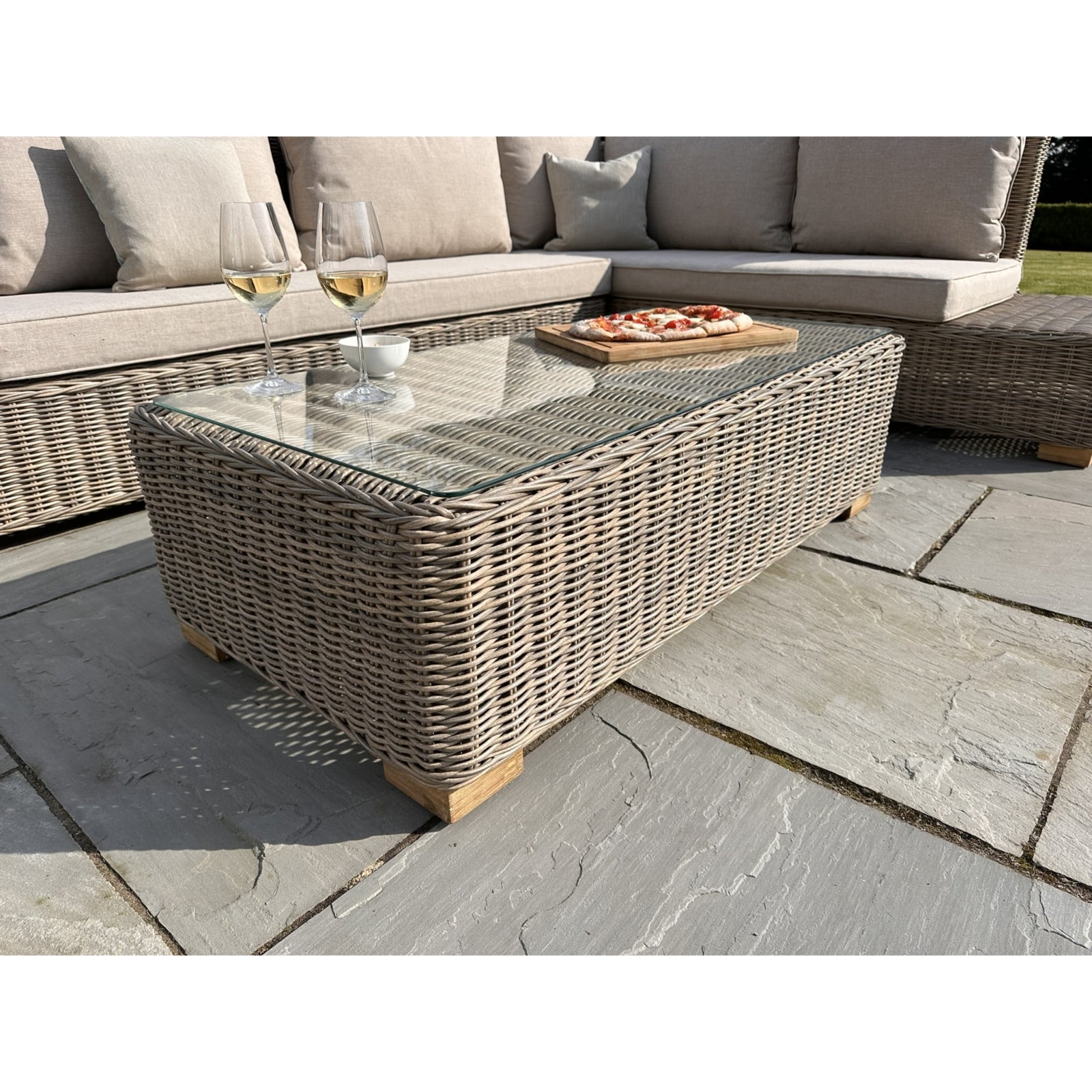 Wicker coffee table on a patio with a sofa and glasses in the background