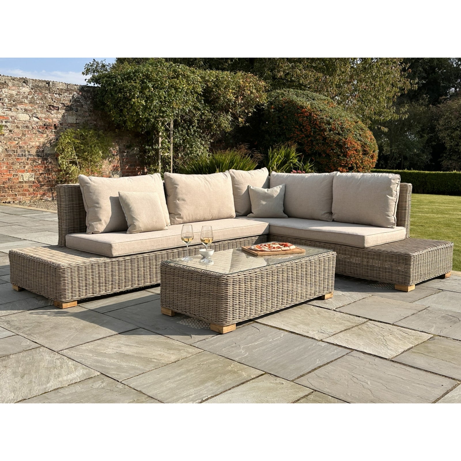 Outdoor patio furniture set with a glass table on a stone patio.