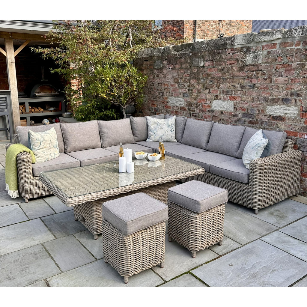 Outdoor patio set with sectional sofa, coffee table, and ottomans on a stone patio.