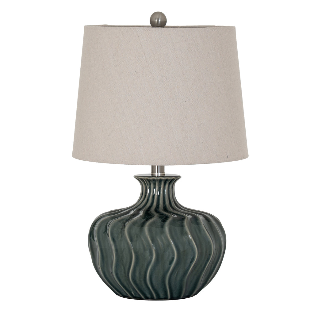 Table lamp with wavy green base and beige lampshade on a white background