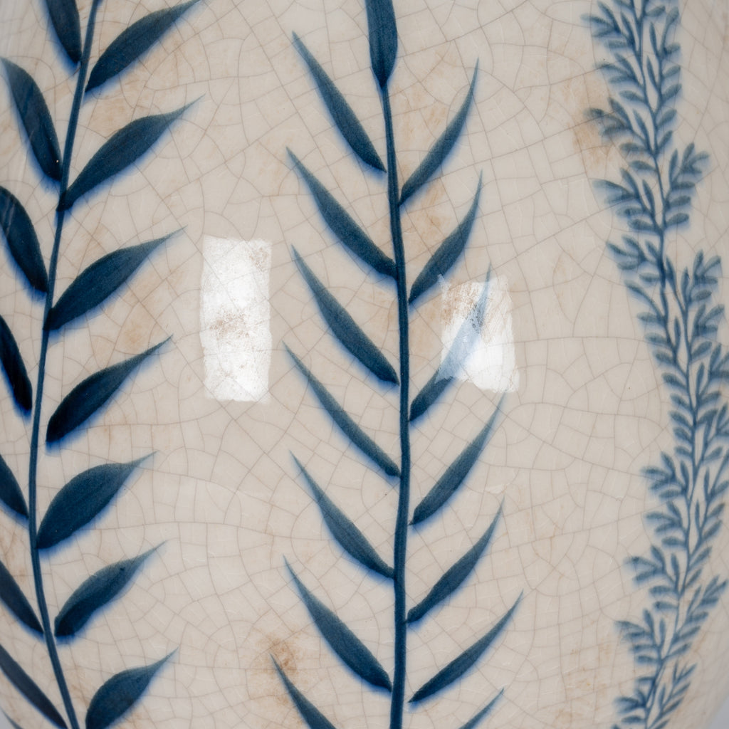 Close-up of a ceramic plate with blue leaf patterns on a beige textured background