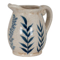 Ceramic pitcher with blue leaf patterns on a white background