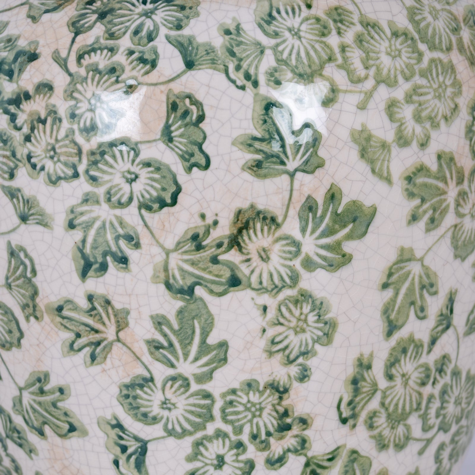 Close-up of a ceramic vase with green floral pattern on a white background